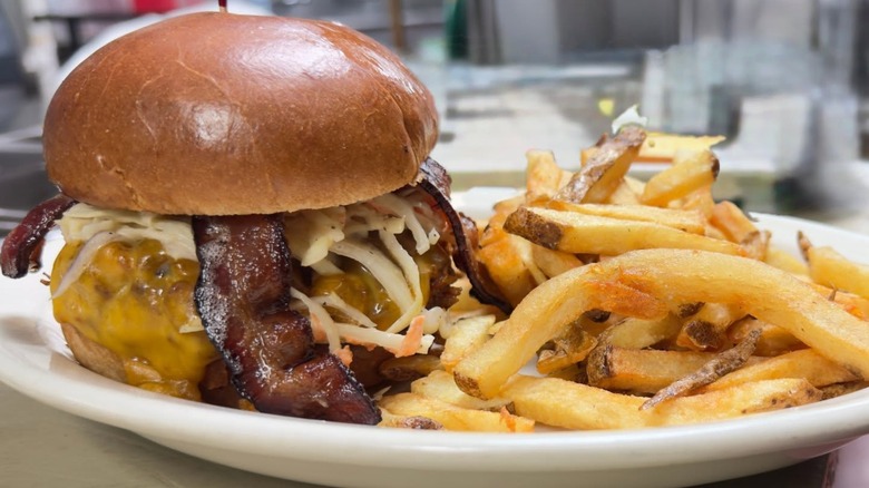Burger with bacon and cheese on plate with fries