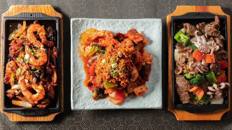 Three dishes with shrimp, beef, and vegetables on table