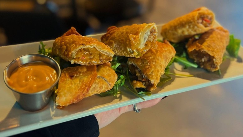 Sliced egg rolls with dipping sauce on long plate