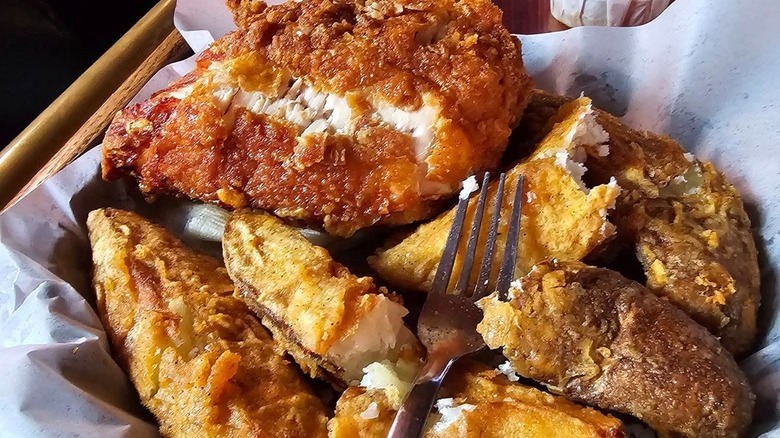 Fried chicken with fries on paper with fork