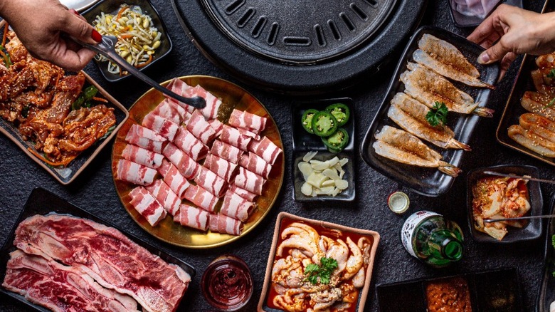 Assortment of raw and marinated meats and vegetables on black table