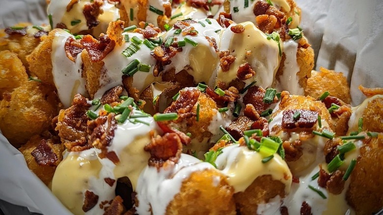Loaded tater tots with sour cream, cheese, bacon, and scallions