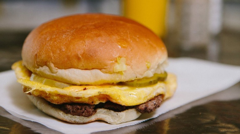 Cheeseburger with egg placed on paper towel in front of blurred background