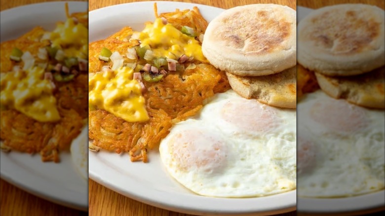 Eggs, a muffin, and hash browns with cheese, onions, and peppers on a plate