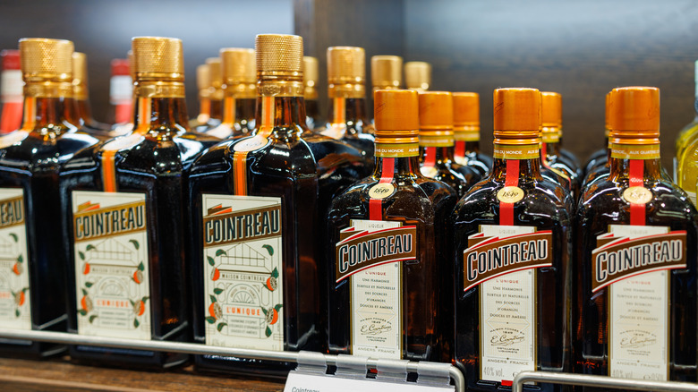 An array of Cointreau bottles on a shelf at a liquor store.
