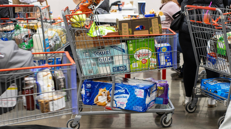 Busy shoppers at Costco with shopping carts ready to line up at checkout.