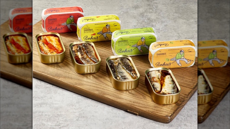 Selection of Pinhais canned sardines opened and displayed on wood board.