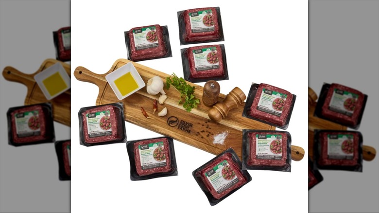 A selection of 100% Grass-Fed New Zealand beef next to cutting board with fresh herbs and spices.