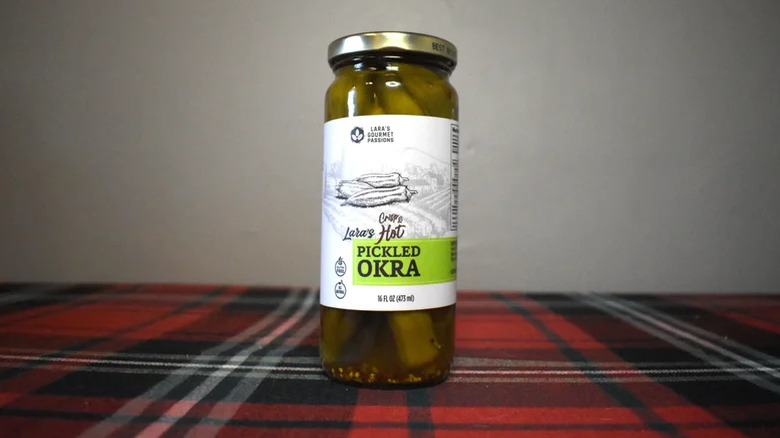 A jar of Lara's crispy hot pickled okra on a tablecloth.
