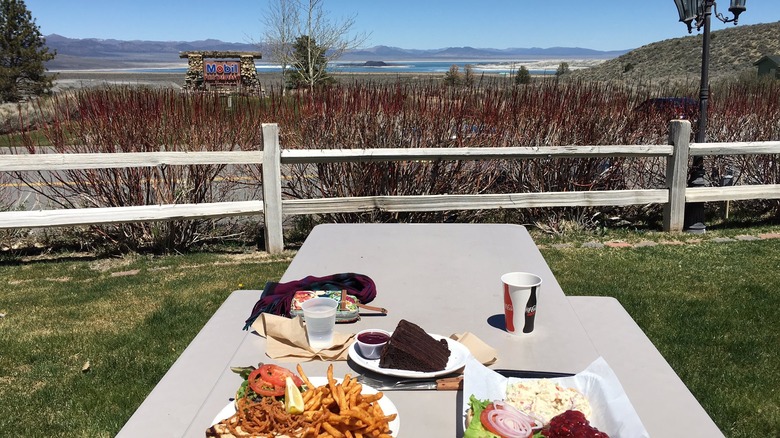 Outdoor scenery featuring a couple of dishes on a table, set against a picturesque background of the deli