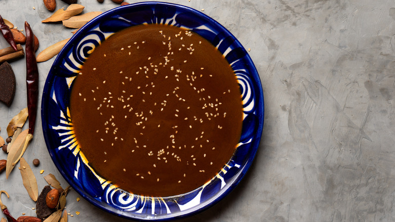 Mole sauce in a blue bowl with ingredients on the table
