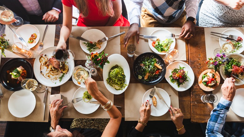 Group of people enjoying a dinner party at long dining table.