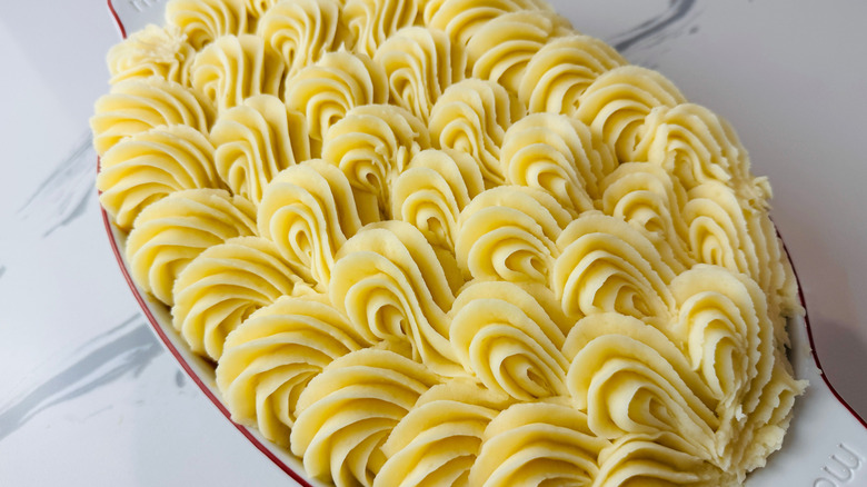 Decoratively piped mashed potatoes in baking dish
