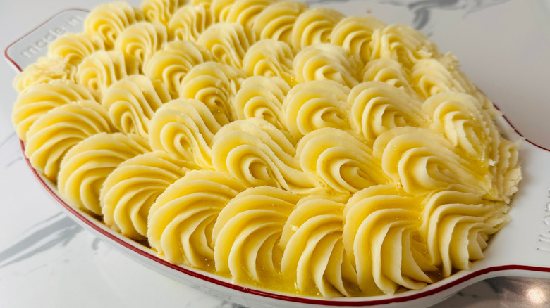 Decoratively piped mashed potatoes in baking dish