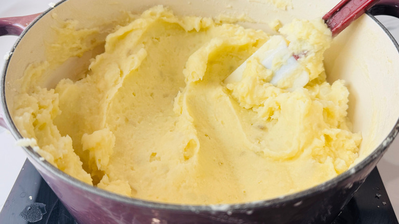 Mashed potatoes in large pot smoothed by rubber spatula
