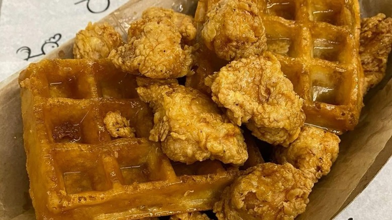 Chicken and waffles in container with syrup.
