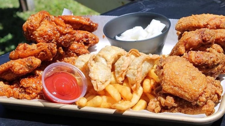 Mixed tray of fried chicken, fries, and dipping sauce.
