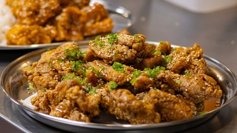 Fried chicken on silver tray with another blurred in background.