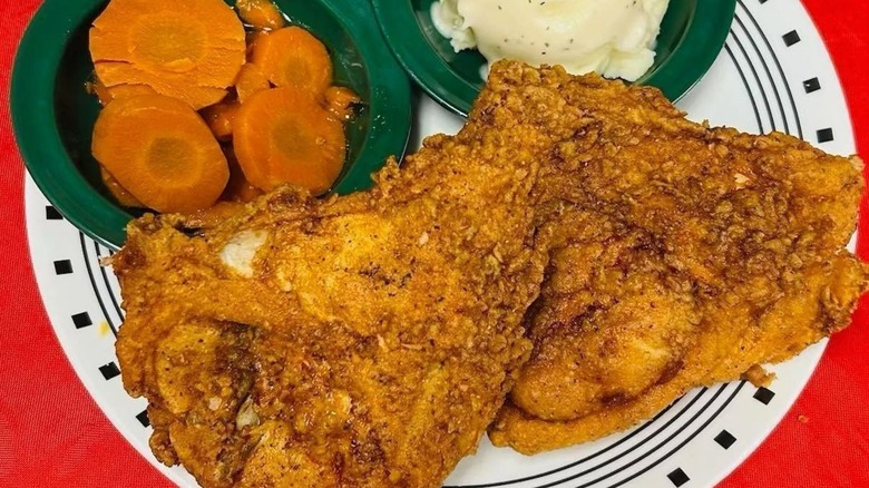 Fried chicken on plate with sides of carrots and mashed potatoes