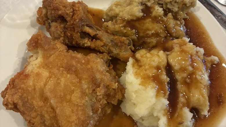 Fried chicken on plate with mashed potatoes, stuffing, and gravy