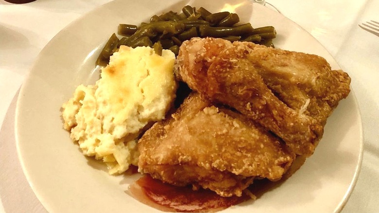 Fried chicken on plate with green beans and mashed potatoes.