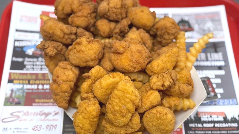 Half chicken, half scallop basket on red tray with blurred advertising.