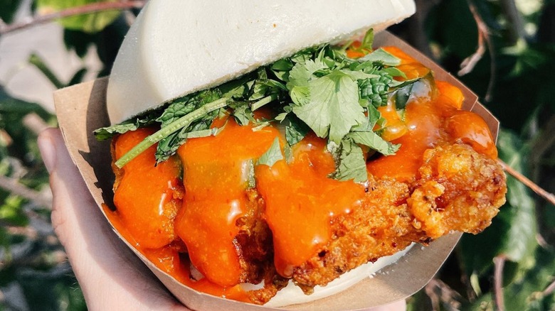 Crispy fried chicken with sauce and greens on bao buns.