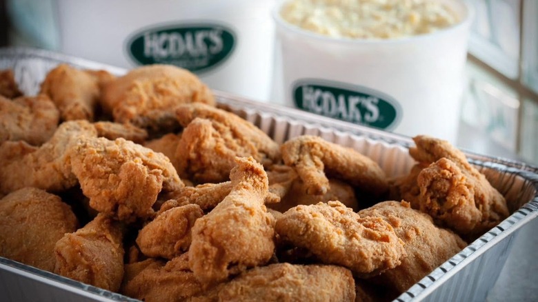 Tray of fried chicken with blurred buckets of sides.