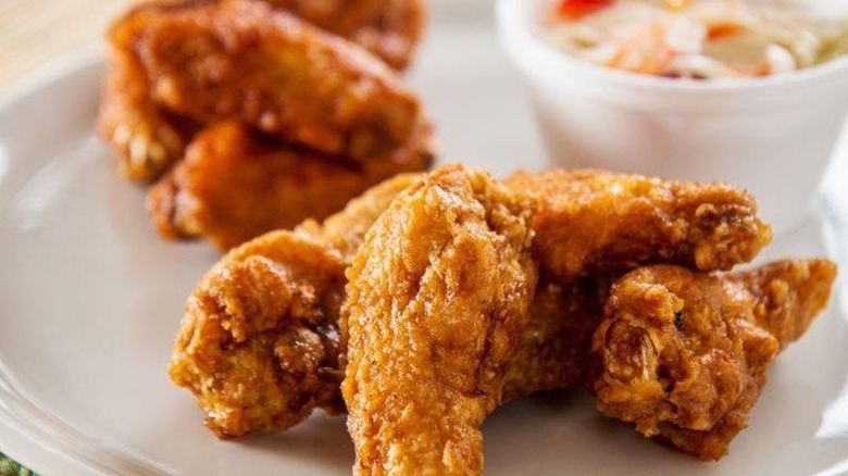 Crispy fried chicken wings on plate with blurred background.