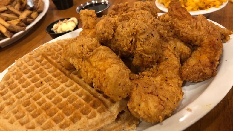 Pile of fried chicken on plate with waffles.