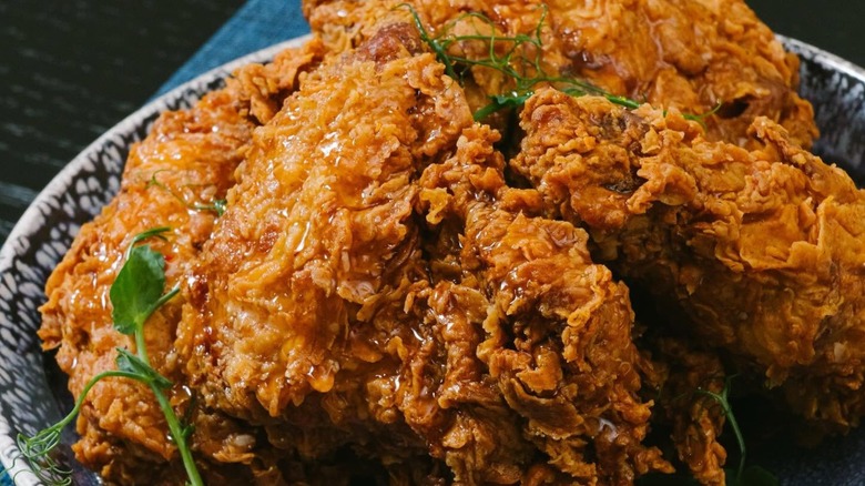 Pieces of fried chicken with honey in bowl.