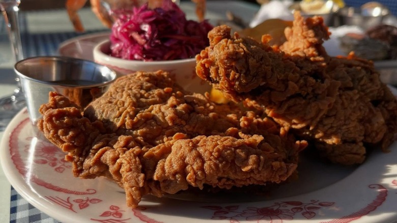 Fried chicken on plate with slaw and sauce.