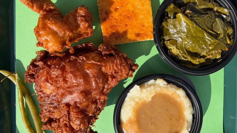 Dark fried chicken with greens, mashed potatoes, and cornbread.