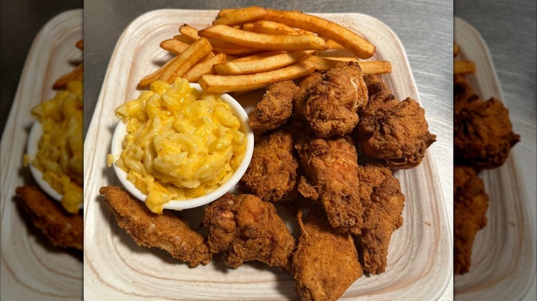 Fried chicken on square plate with fries and mac and cheese.