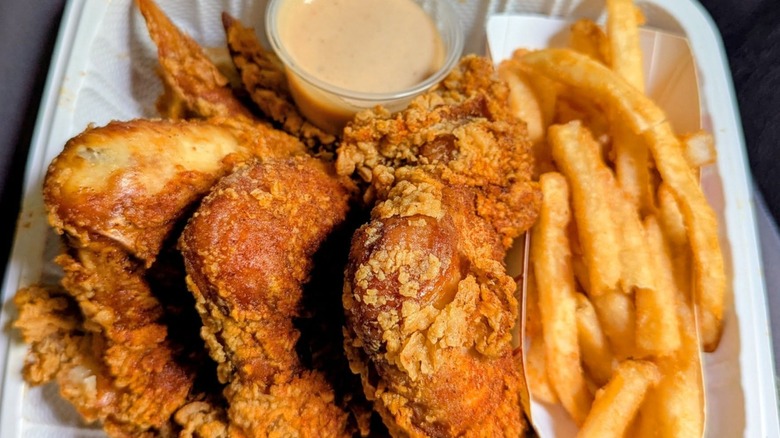 Fried chicken, fries, and sauce in styrofoam container
