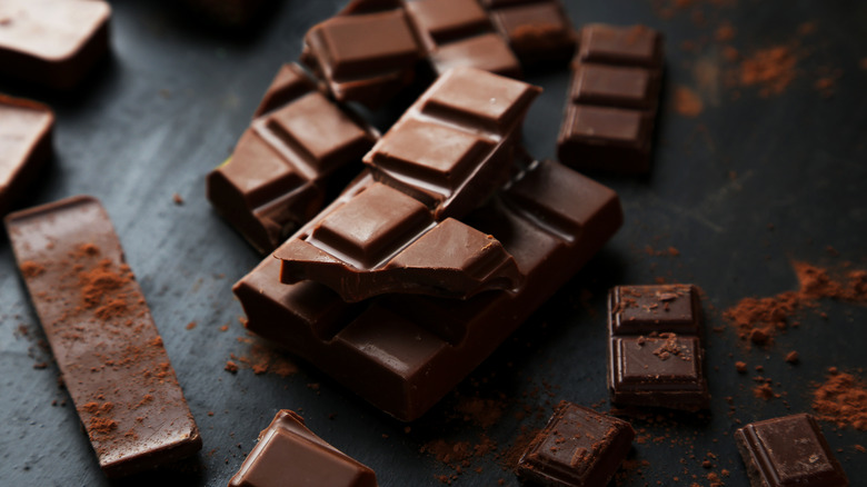 Chocolate chunks sprinkled with cocoa powder on dark background