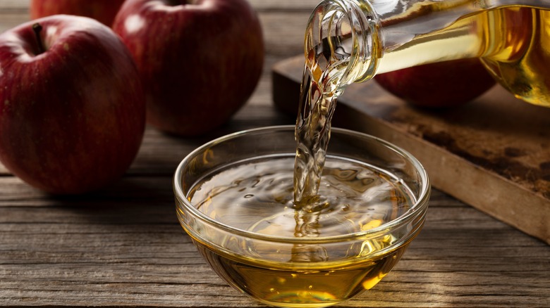 Pouring apple cider vinegar into a glass bowl