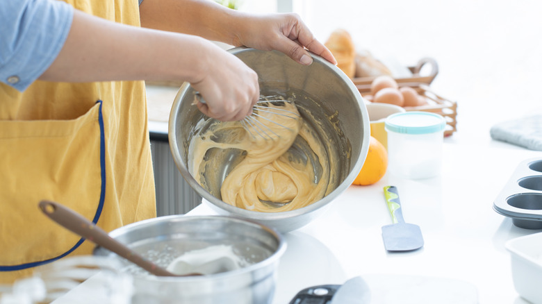 Baker pouring cake batter into a pan