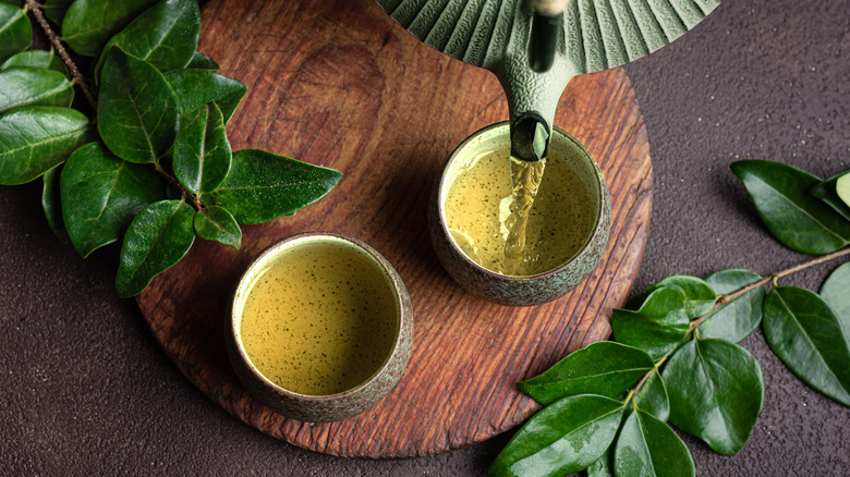 Pouring green tea into two cups.