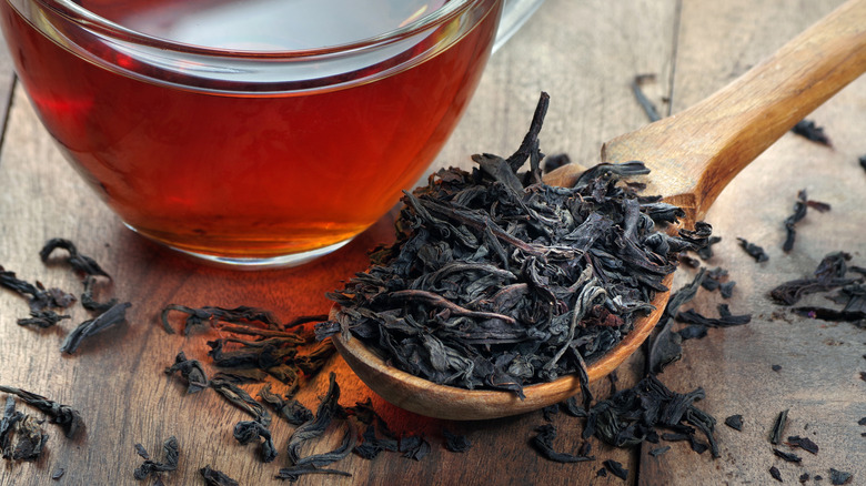 Black tea leaves next to a cup of tea