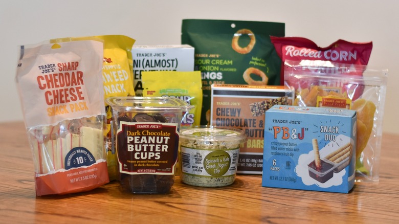 A collection of packaged Trader Joe's snacks is on a wooden table.