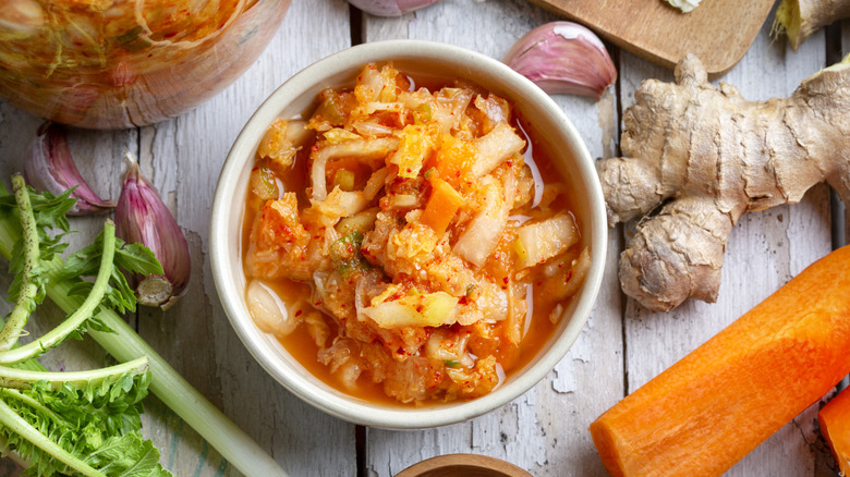 Kimchi in a bowl surrounded by vegetables