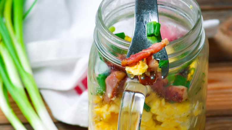 Eggs and scallions and bacon in a mason jar with fork