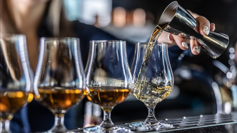 A bartender pouring whiskey into glasses