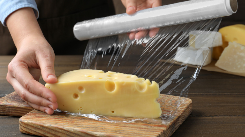 Wrapping a large wedge of cheese in plastic wrap