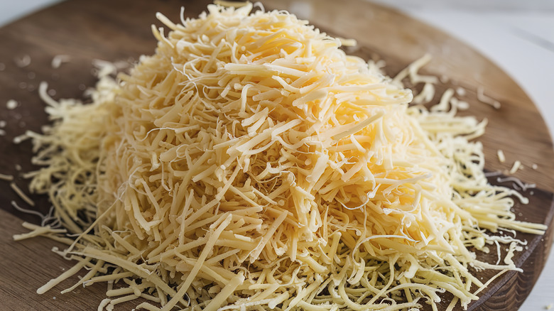 Shredded cheese on a wooden cutting board