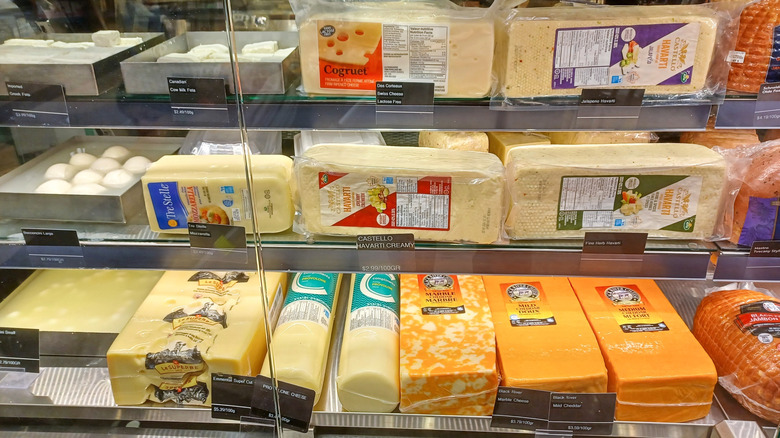A deli counter with bulk blocks and loaves of cheese