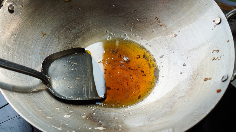 A recently used, greasy wok with leftover oil.