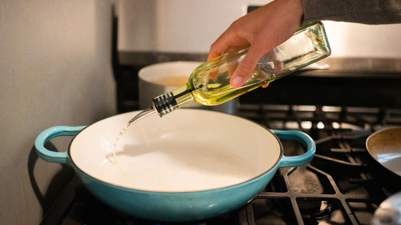 Person pouring oil into pan