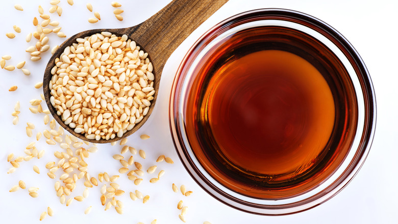 A spoonful of sesame seeds next to a small bowl of oil
